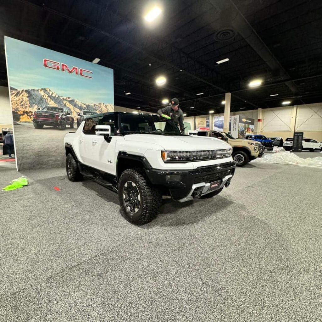 Technician detailing a Hummer EV on a car show floor