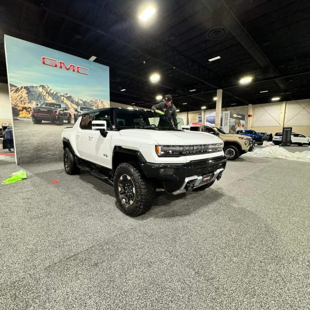 Technician detailing a Hummer EV on a car show floor